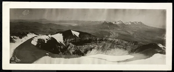 Panoramic view from above of a range of snowcapped mountains, and what appears to be the rim of a volcano, presumably on or near the Panama Canal, 1913